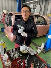 西崎自動車の整備工場で自動車部品を手にする夏目さん